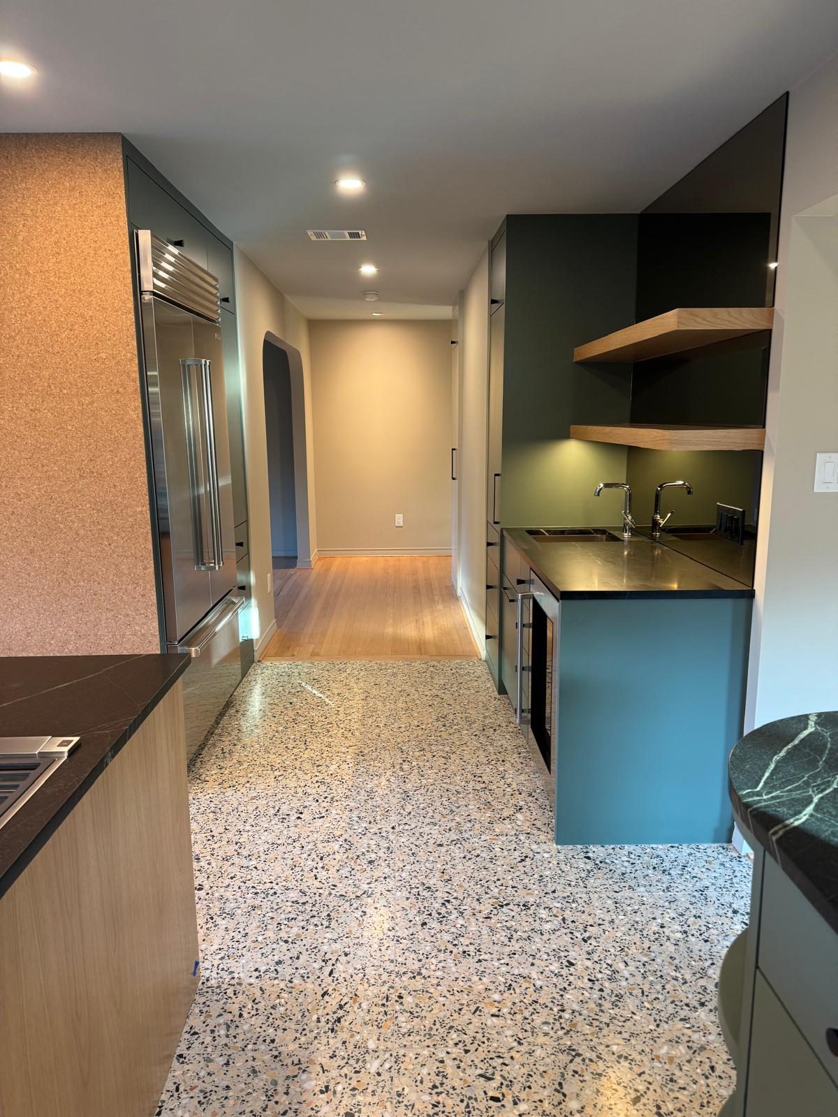Butler pantry with floating shelves, terrazzo floor, and sage cabinetry