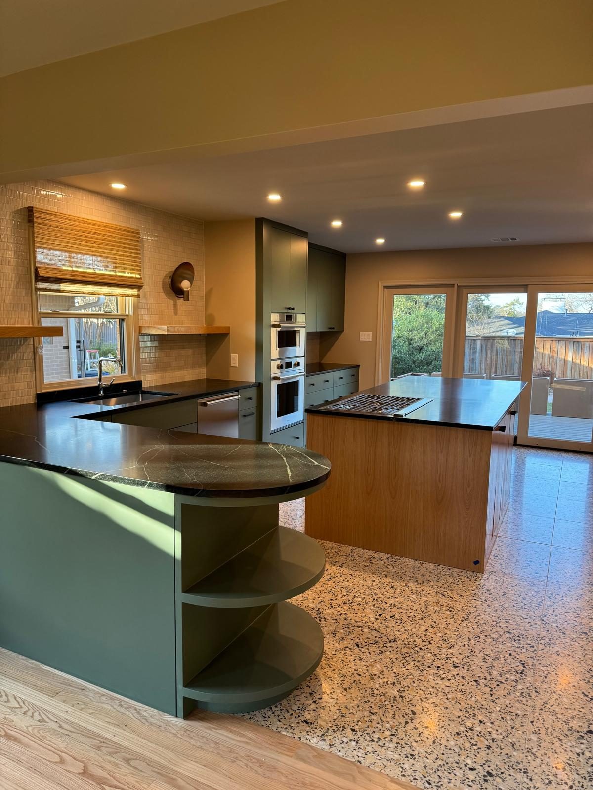 Kitchen with sage-green cabinets, black stone counters, and terrazzo floors